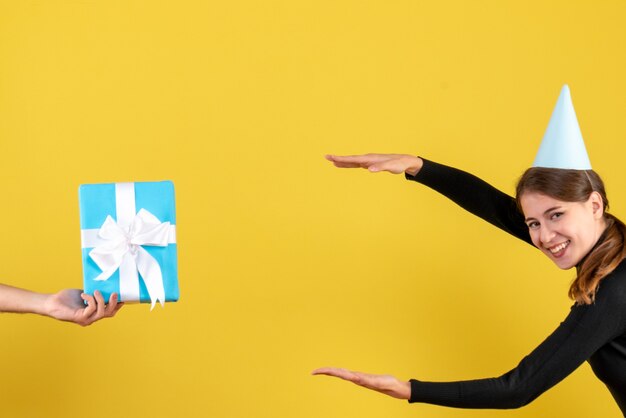 Vorderansicht glückliches junges Mädchen mit Partykappe, die versucht, die Größe der blauen Geschenkbox zu zeigen