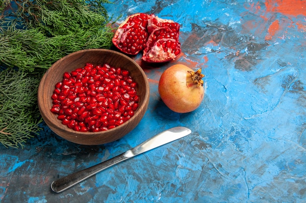 Vorderansicht granatapfelkerne in schüssel abendessen messer ein geschnittener granatapfel auf blau