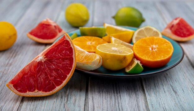 Vorderansicht Grapefruitkeile mit Zitronenlimette und Orangenschnitzen auf einem Teller auf grauem Hintergrund