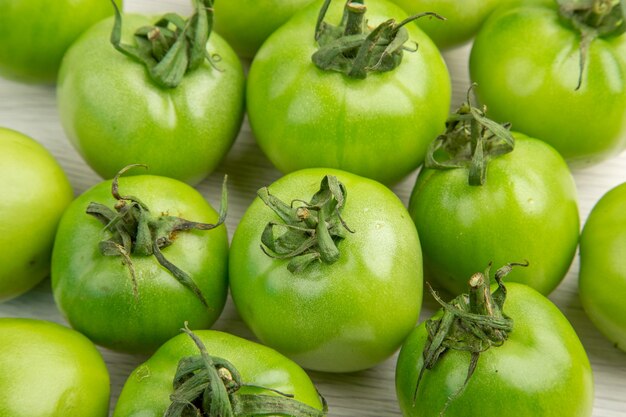 Vorderansicht grüne Tomaten auf weißem Schreibtisch Farbe reife Salatfotomahlzeit gesunde Lebensdiät