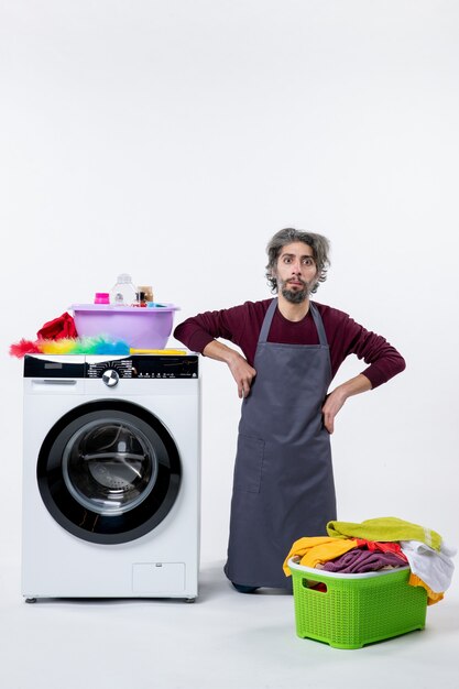 Vorderansicht Haushälter Mann kniet in der Nähe von Waschmaschine auf weißem Hintergrund