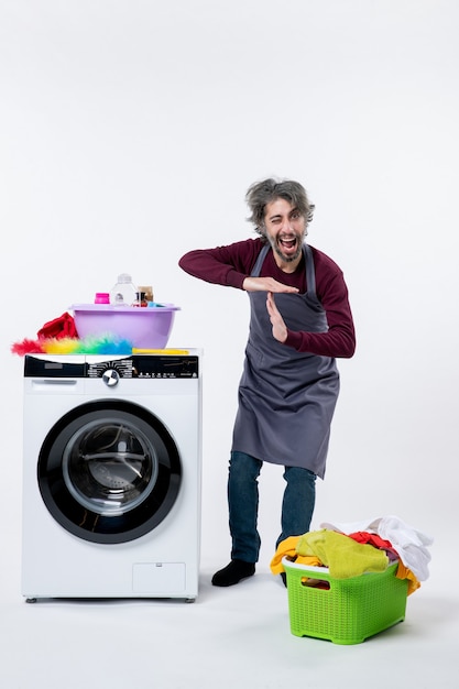 Vorderansicht Haushälter Mann steht in der Nähe von Wäschekorb der weißen Waschmaschine auf dem Boden