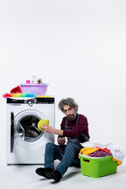 Vorderansicht Haushälterin Mann Wäsche in Waschmaschine auf weißem Hintergrund