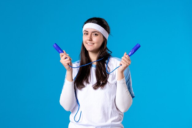 Vorderansicht hübsche Frau in der Sportkleidung mit Springseil auf Blau