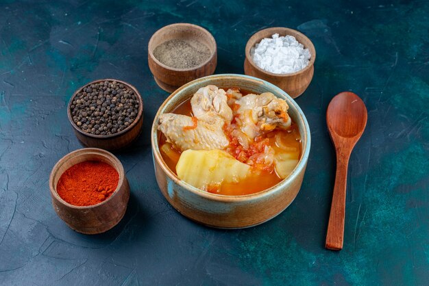 Vorderansicht Hühnersuppe mit Kartoffeln zusammen mit Salzpfeffergewürzen auf der dunkelblauen Oberflächensuppe Fleischessen Abendessen