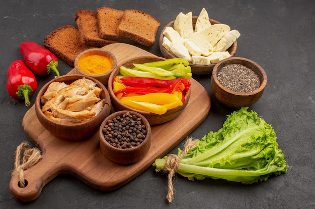 Vorderansicht in Scheiben geschnittene Paprika mit dunklen Brotlaiben auf dunklem Raum