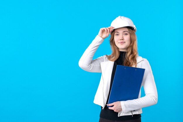 Vorderansicht junge Architektin im Helm auf Blau