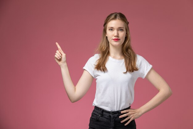 Vorderansicht junge attraktive Frau gerade einfach posierend im weißen T-Shirt auf der rosa Wandmodellfarbe weibliches junges Mädchen