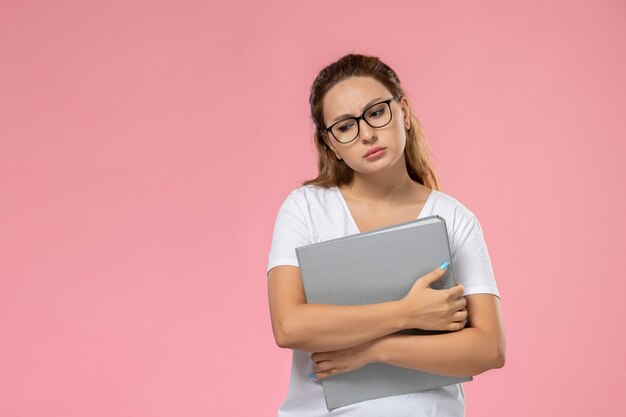 Vorderansicht junge attraktive Frau im weißen T-Shirt, das graue Dateien hält und auf dem rosa Hintergrund denkt