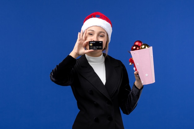 Vorderansicht junge Dame mit Baumspielzeug und Bankkarte auf Neujahrs-Emotionsfeiertagen der blauen Wand