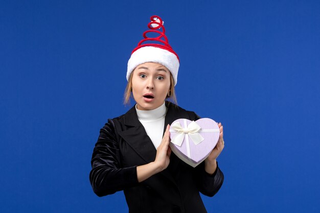 Vorderansicht junge Dame mit herzförmigem Geschenk auf blauem Neujahrsfeiertagsgeschenk der Wand