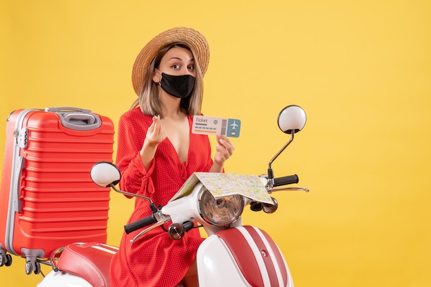 Vorderansicht junge Dame mit schwarzer Maske auf Moped mit Ticket zum Geldverdienen
