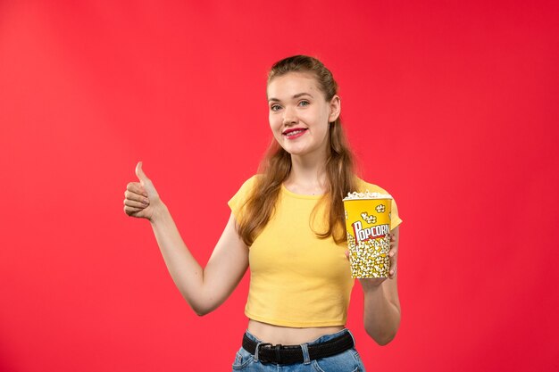 Vorderansicht junge Frau am Kino, die Popcorn auf rotem Schreibtisch Kino Kino weiblicher Spaßfilm hält