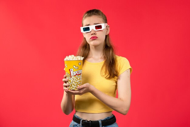 Vorderansicht junge Frau am Kino, die Popcorn-Paket in -d Sonnenbrille auf der roten Wand Filmtheater Kino Kino Mädchen hält