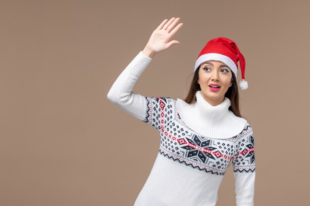 Vorderansicht junge Frau Begrüßung und Winken auf braunem Hintergrund Emotion Neujahr Weihnachten