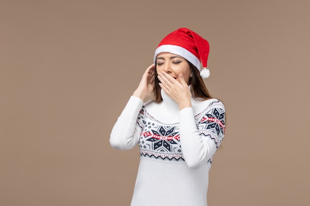 Vorderansicht junge Frau, die auf braunem Hintergrundweihnachtsgefühl Neujahr gähnt