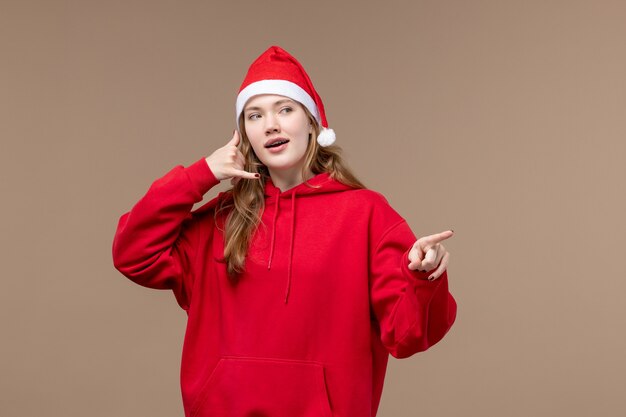 Vorderansicht junge Frau, die auf Weihnachtsfeindlichkeitsfeiertag des braunen Hintergrunds aufwirft