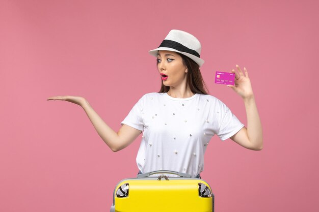 Vorderansicht junge Frau, die Bankkarte auf der rosa Wandfrauenurlaubsgeldreise hält