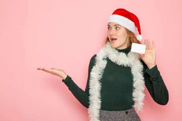 Vorderansicht junge Frau, die Bankkarte auf rosa Wandfarbe Emotion Modellfeiertag Weihnachten Neujahr hält