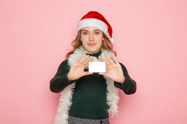 Vorderansicht junge Frau, die Bankkarte auf rosa Wandmodellfeiertag Weihnachten s hält