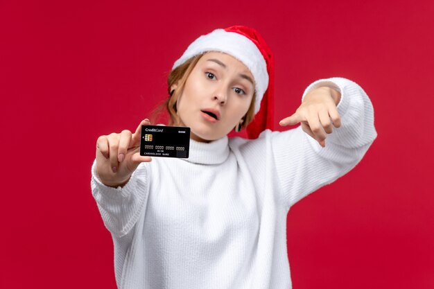 Vorderansicht junge Frau, die Bankkarte auf rotem Hintergrund hält