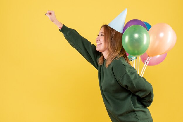 Vorderansicht junge Frau, die bunte Luftballons versteckt