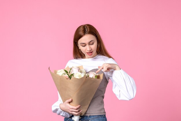 Vorderansicht junge Frau, die einen Strauß schöner Rosen auf rosa Marschparfüm hält