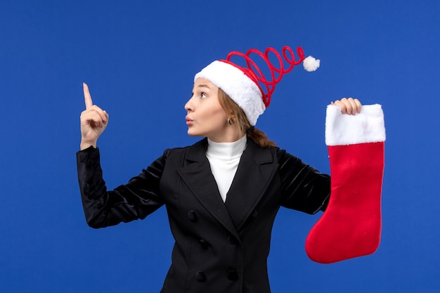 Vorderansicht junge Frau, die große rote Socke auf menschlichem Neujahrsfeiertag der blauen Wand hält