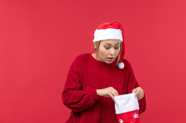 Vorderansicht junge Frau, die große Weihnachtssocke öffnet, Weihnachtsfeiertag rot