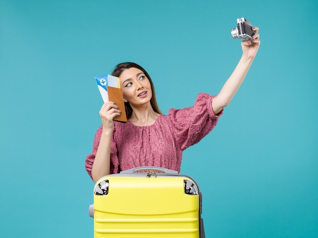 Vorderansicht junge Frau, die im Urlaub hält Kamera hält Foto auf hellblauer Hintergrundreise Urlaub Frau im Ausland Meer
