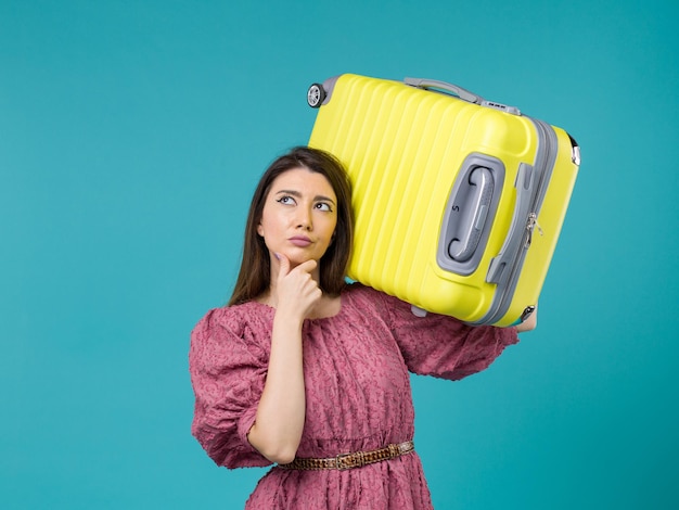 Vorderansicht junge Frau, die in den Urlaub mit ihrer großen Tasche auf dem blauen Hintergrund Sommerreise Frau See Urlaubsreise geht