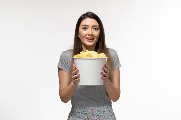Vorderansicht junge Frau, die Kartoffelchips hält und Film auf weißer Oberfläche sieht