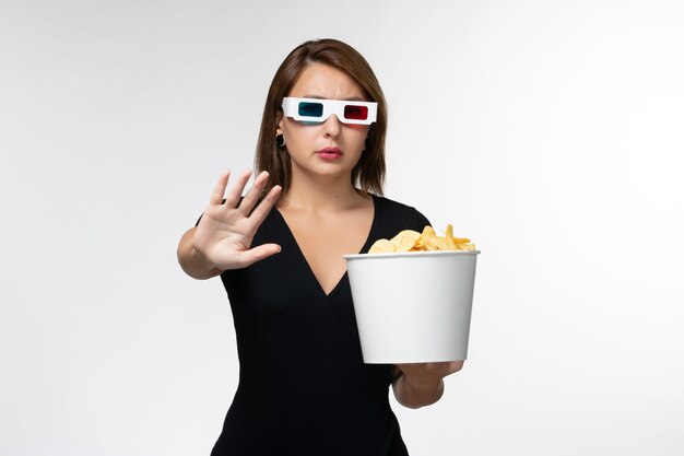 Vorderansicht junge Frau, die Kartoffelchips in d Sonnenbrille hält und Film auf weißer Oberfläche sieht