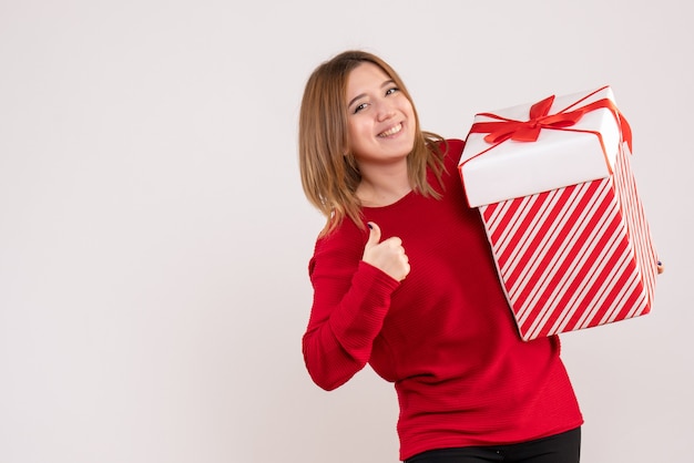 Kostenloses Foto vorderansicht junge frau, die mit geschenk in ihren händen steht