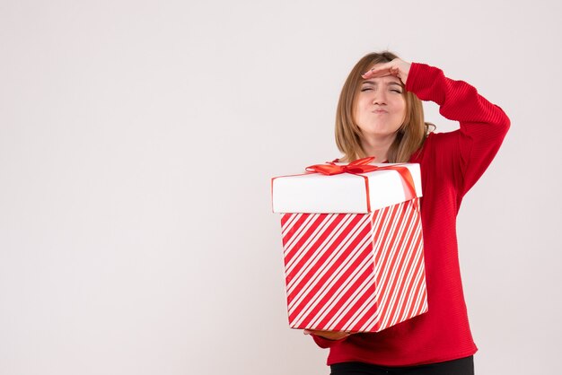 Vorderansicht junge Frau, die mit Geschenkbox in ihren Händen steht