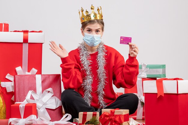 Vorderansicht junge Frau, die mit Weihnachtsgeschenken in der Maske sitzt