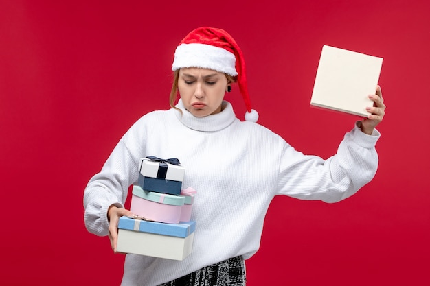 Vorderansicht junge Frau, die Neujahrsgeschenke auf rotem Schreibtisch hält