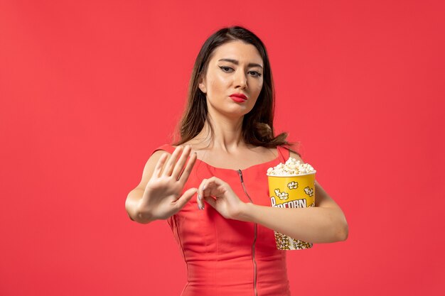 Vorderansicht junge Frau, die Popcorn auf der roten Oberfläche hält