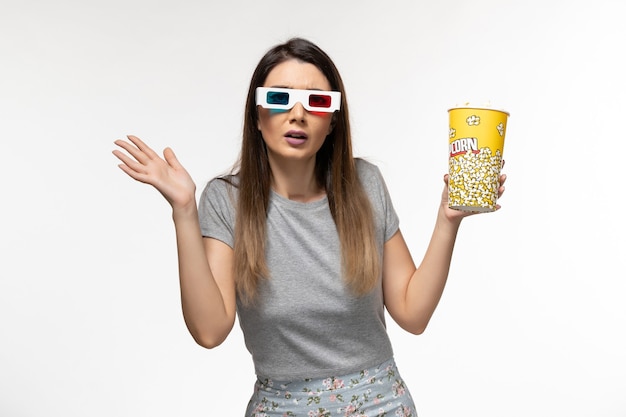 Vorderansicht junge Frau, die Popcorn isst und Film in d Sonnenbrille auf der hellen weißen Oberfläche sieht