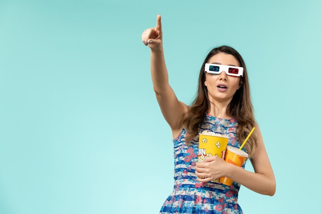 Vorderansicht junge Frau, die Popcorngetränk in d Sonnenbrille auf der blauen Oberfläche hält