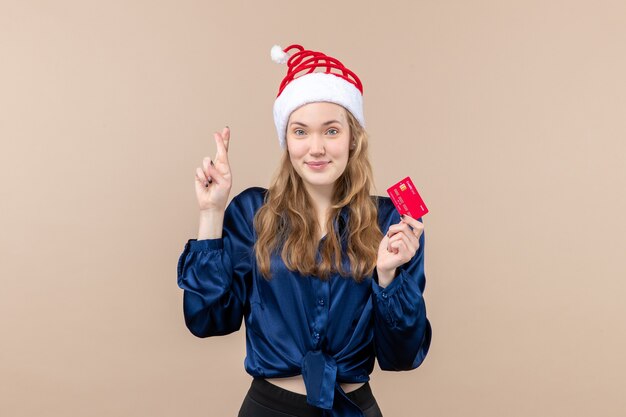 Vorderansicht junge Frau, die rote Bankkarte auf dem rosa Hintergrundfeiertags-Weihnachtsgeldfoto-Neujahrsgefühl hält