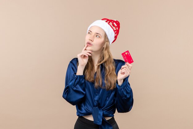 Vorderansicht junge Frau, die rote Bankkarte auf dem rosa Hintergrundweihnachtsfoto-Feiertags-Neujahrsgefühl hält