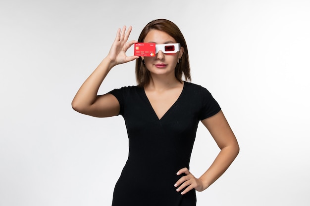 Vorderansicht junge Frau, die rote Bankkarte in d Sonnenbrille auf der hellen weißen Oberfläche hält