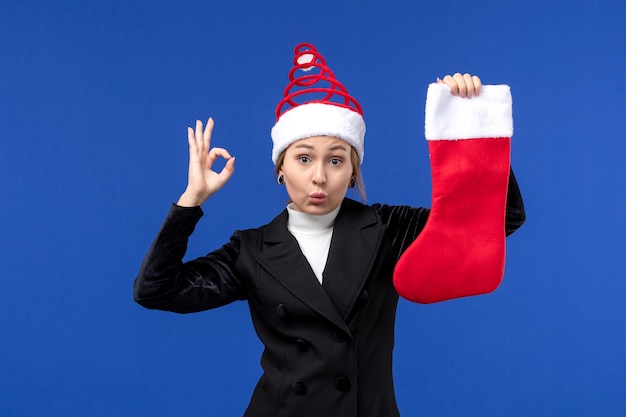 Kostenloses Foto vorderansicht junge frau, die rote weihnachtssocke auf neujahrsmensch der blauen wandferien hält