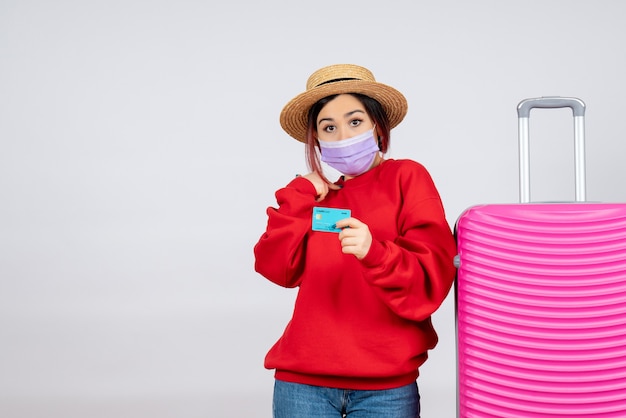 Vorderansicht junge Frau, die sich auf die Reise in der Maske auf der weißen Wand vorbereitet