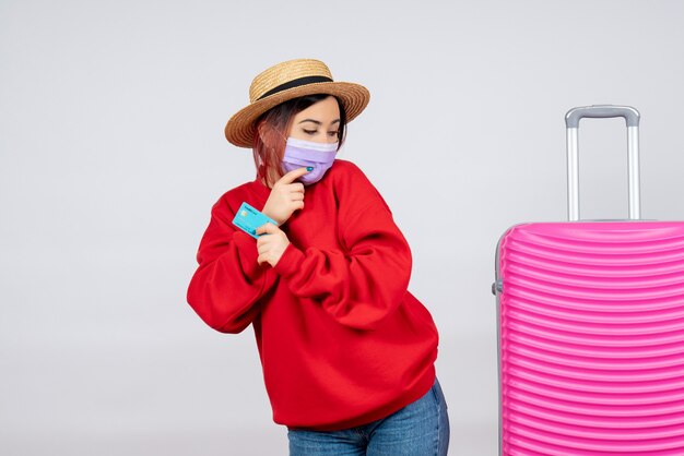 Vorderansicht junge Frau, die sich auf die Reise in der Maske auf der weißen Wand vorbereitet