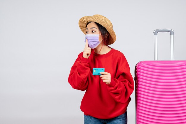 Vorderansicht junge Frau, die sich auf die Reise in der Maske auf der weißen Wand vorbereitet