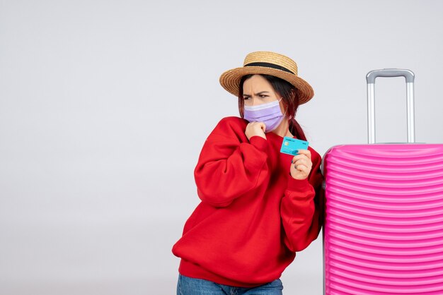 Vorderansicht junge Frau, die sich auf die Reise in der Maske auf der weißen Wand vorbereitet