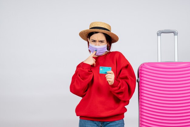 Vorderansicht junge Frau, die sich auf die Reise in der Maske auf der weißen Wand vorbereitet