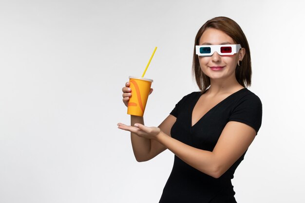 Vorderansicht junge Frau, die Soda in d Sonnenbrille auf weißer Oberfläche hält